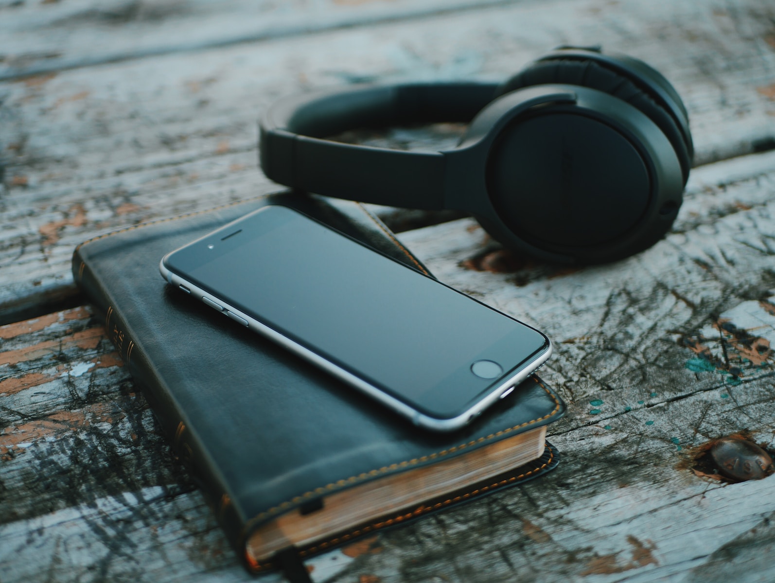 space gray iPhone 6 on book near black wireless headphones